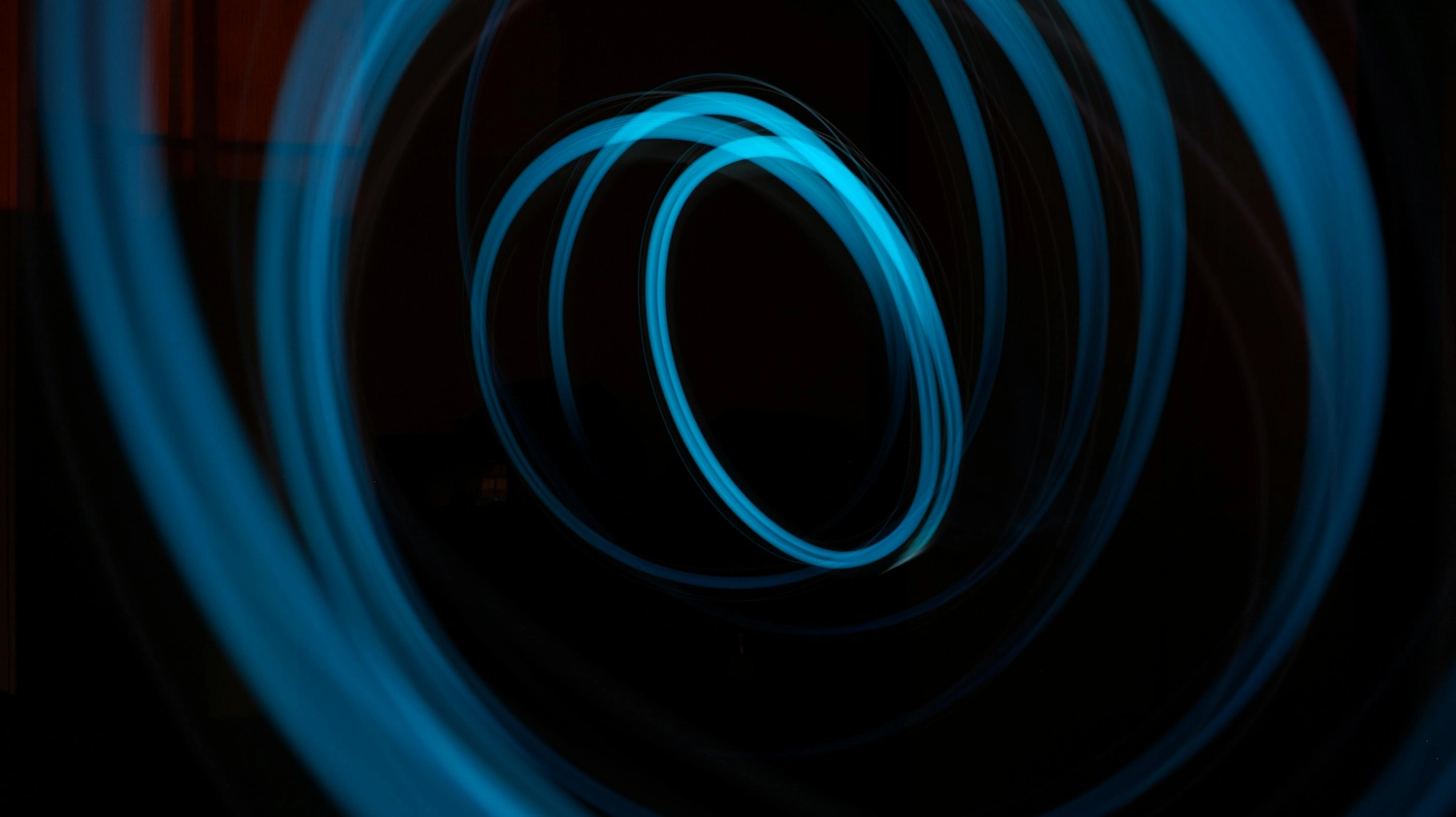 Energieberatung - Energieeinkaufsmanagement - Wirbelnde blaue Lichtspuren vor schwarzem Hintergrund.